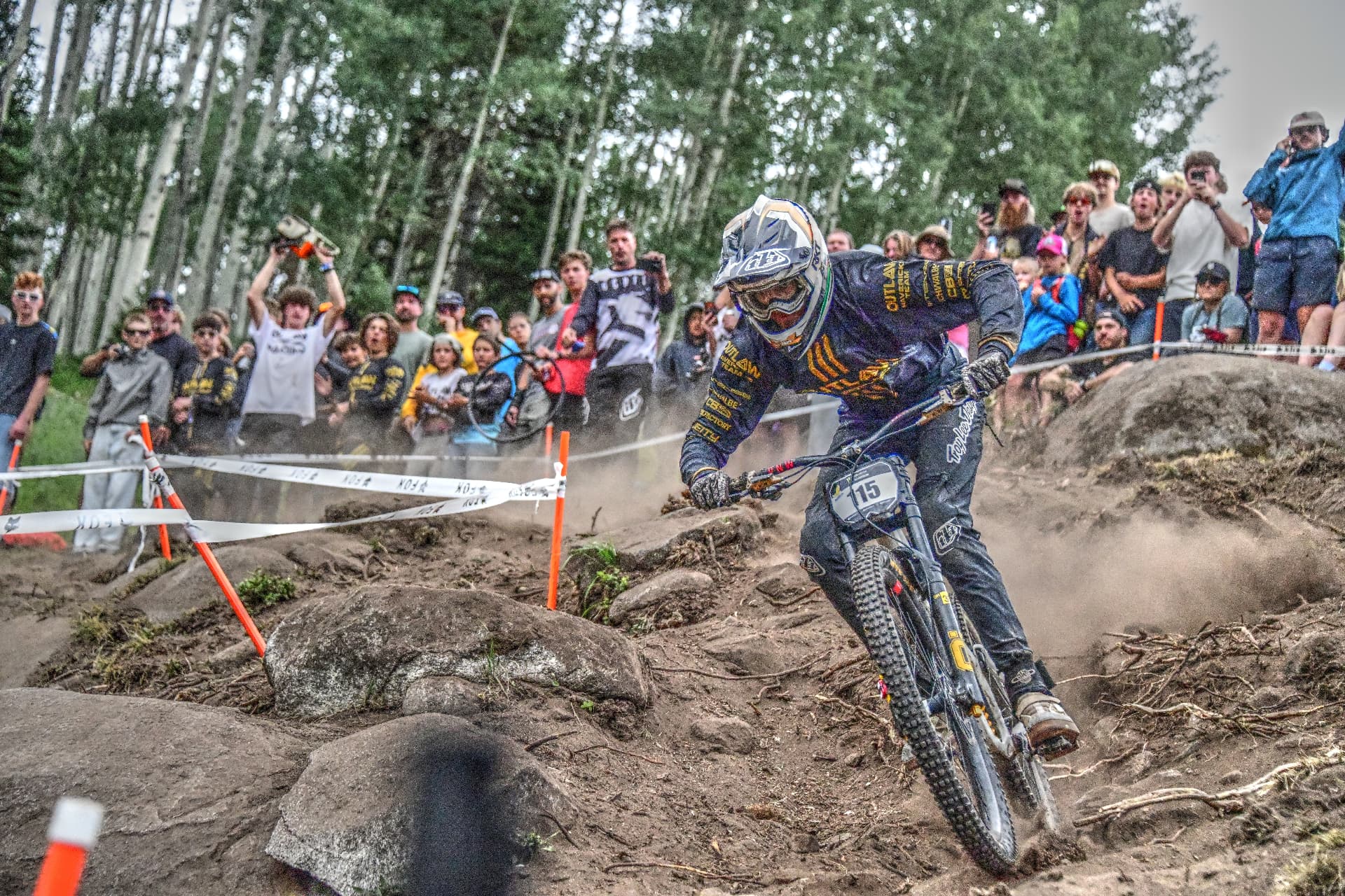 Nico Pfeifer railing a rocky downhill corner in front of spectators